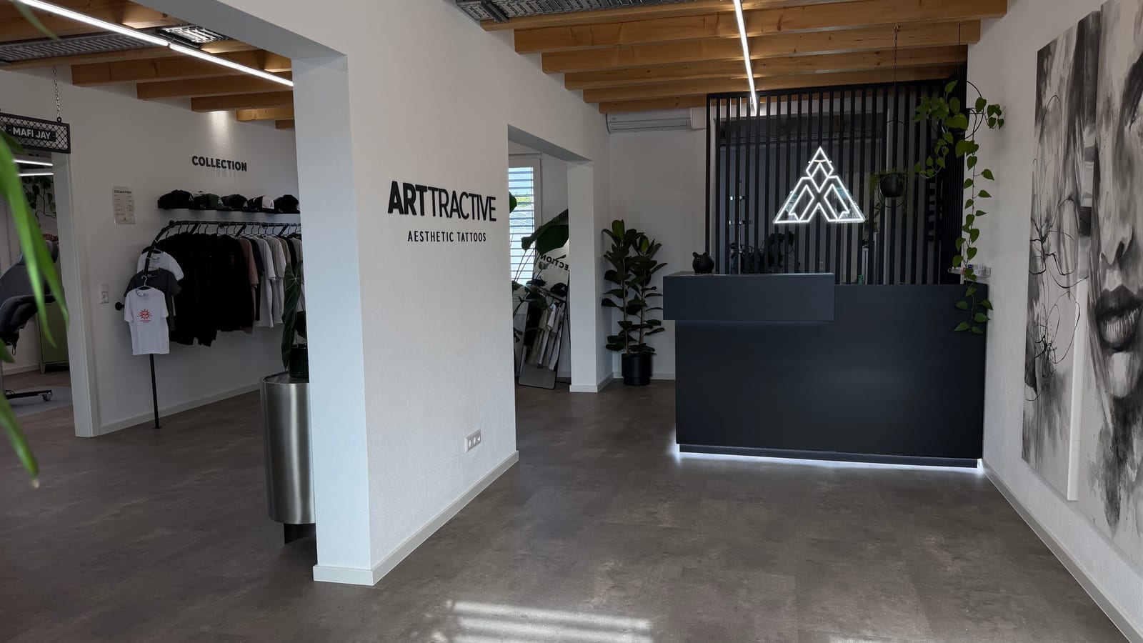 Empfangsbereich mit dem Arttractive-Schriftzug an der Wand und dem Tresen mit leuchtendem Logo