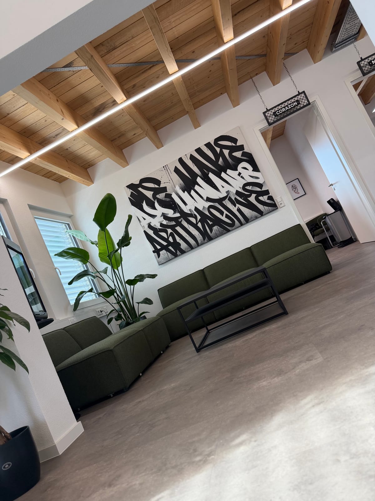 Lounge mit grünem Sofa, Couchtisch und großem Kalligrafie-Bild